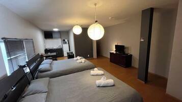 A hotel room with two beds, a TV, a desk, and a wardrobe.