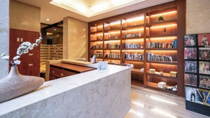 Une bibliothèque moderne dotée d’un comptoir d’accueil en marbre, d’étagères en bois et d’une grande variété de livres et de magazines.