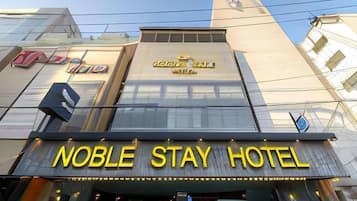 The exterior of the Noble Stay Hotel with a prominent sign and a modern facade.