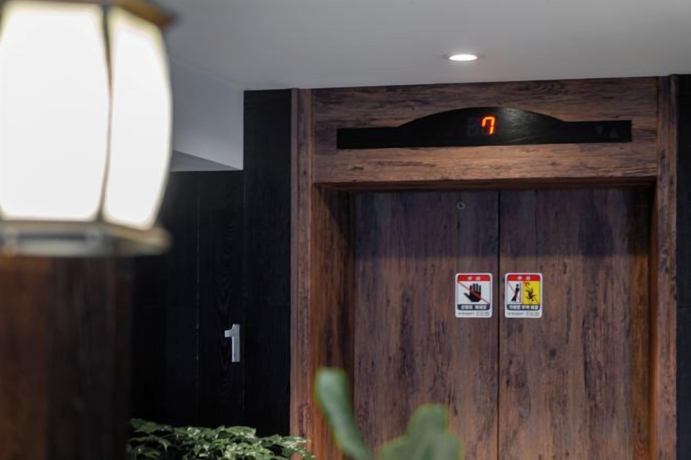 A wooden door with a digital display above it and two safety signs on the door.