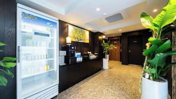 A reception area with a refrigerator, a coffee machine, and a plant.