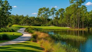 A golf course with a water body, surrounded by tall trees and well-maintained grass. - Horse Creek Retreat (Fort Myers)