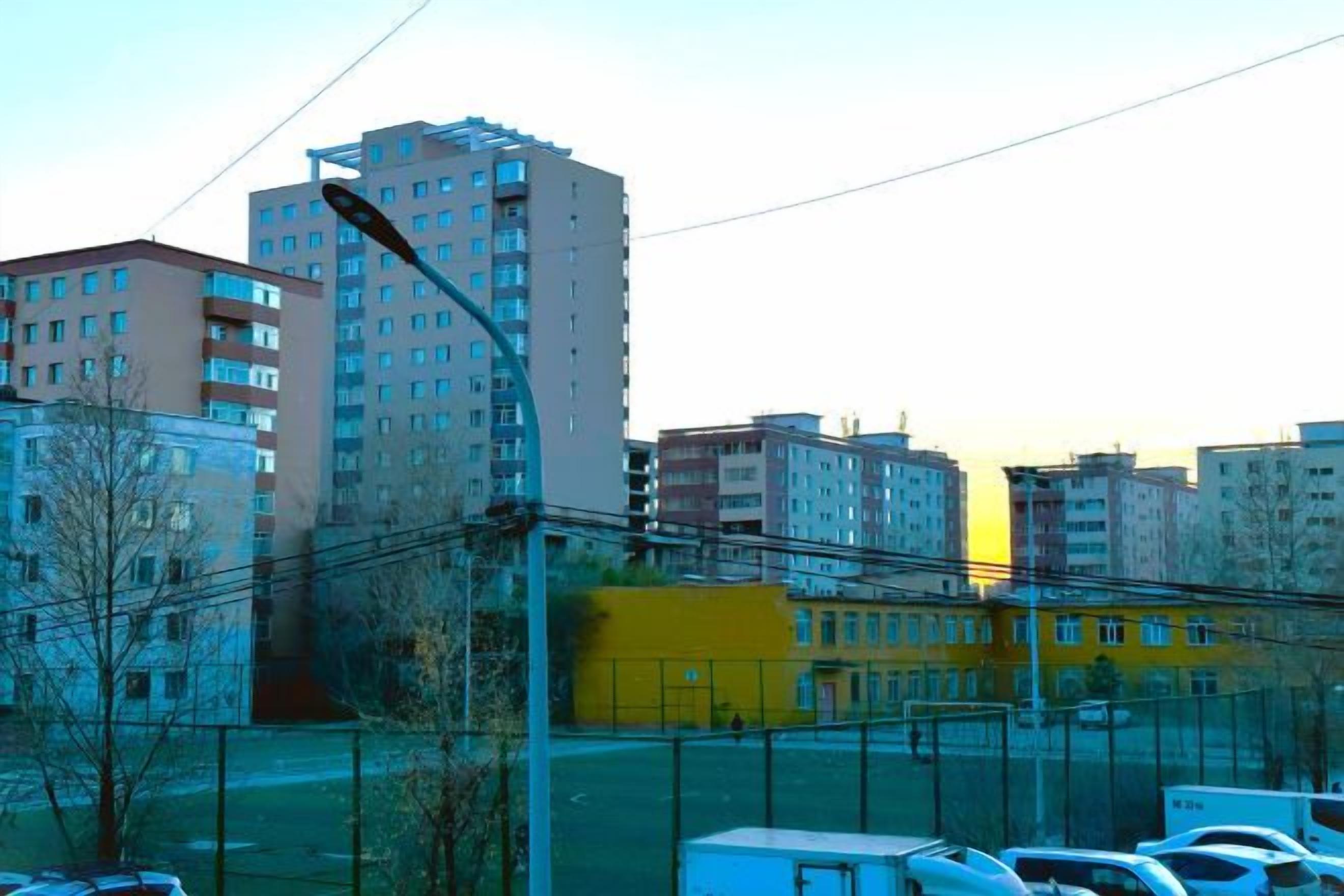 A cityscape with high-rise buildings, a yellow building, and parked cars.