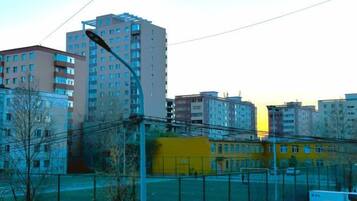 A cityscape with high-rise buildings, a yellow building, and parked cars.