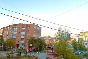 A multi-story building with a playground in the foreground. - Apartment 44, spacious living area, separate kitchen & 1 bedroom (Ulaanbaatar)