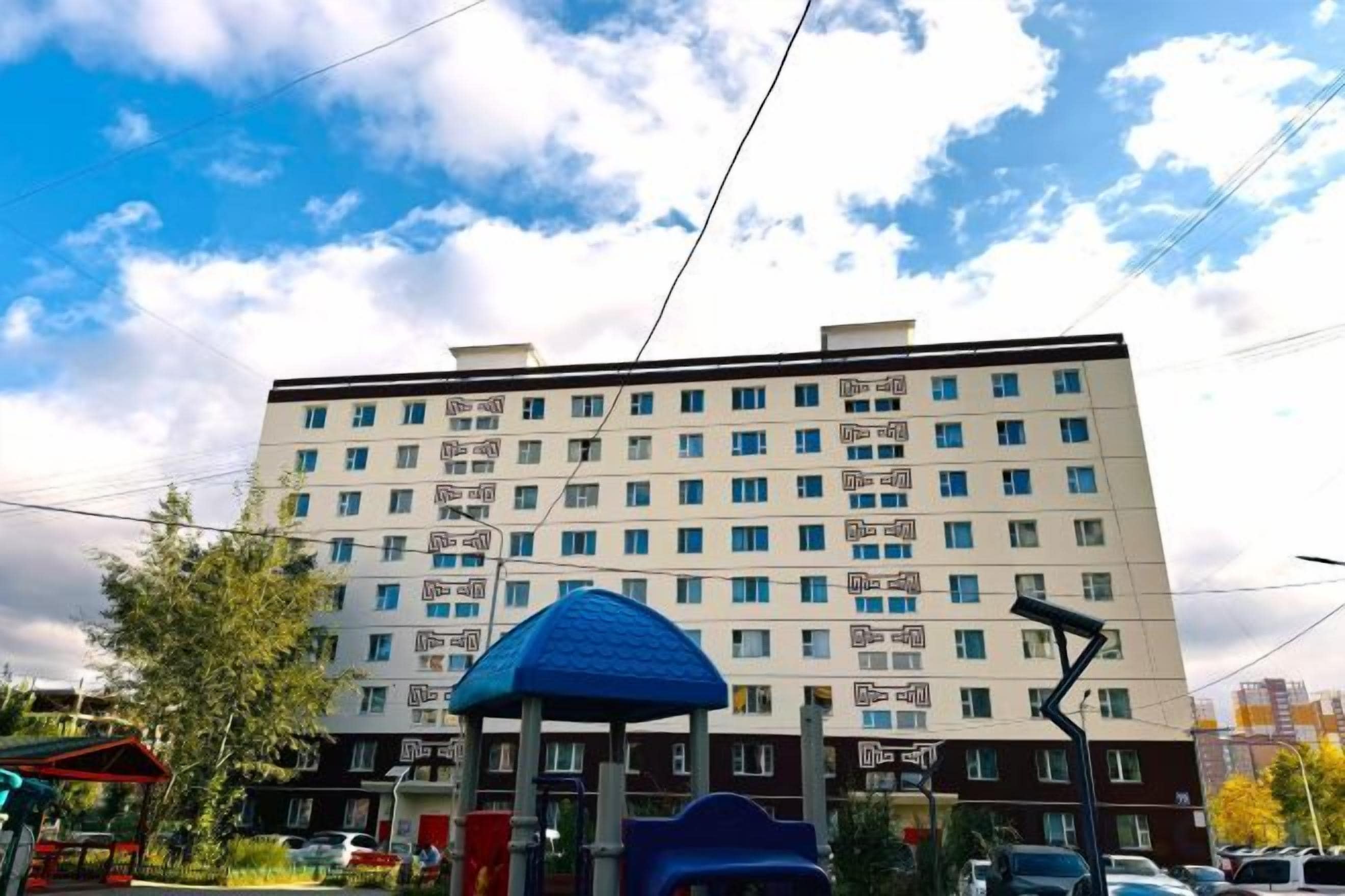 A multi-story building with a flat facade, several windows, and a blue structure in the foreground.