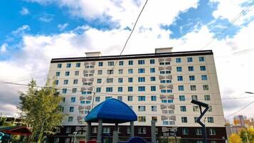 A multi-story building with a flat facade, several windows, and a blue structure in the foreground.