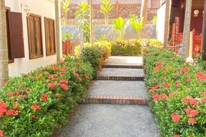 Un chemin bordé de fleurs rouges menant à l’entrée d’un bâtiment.