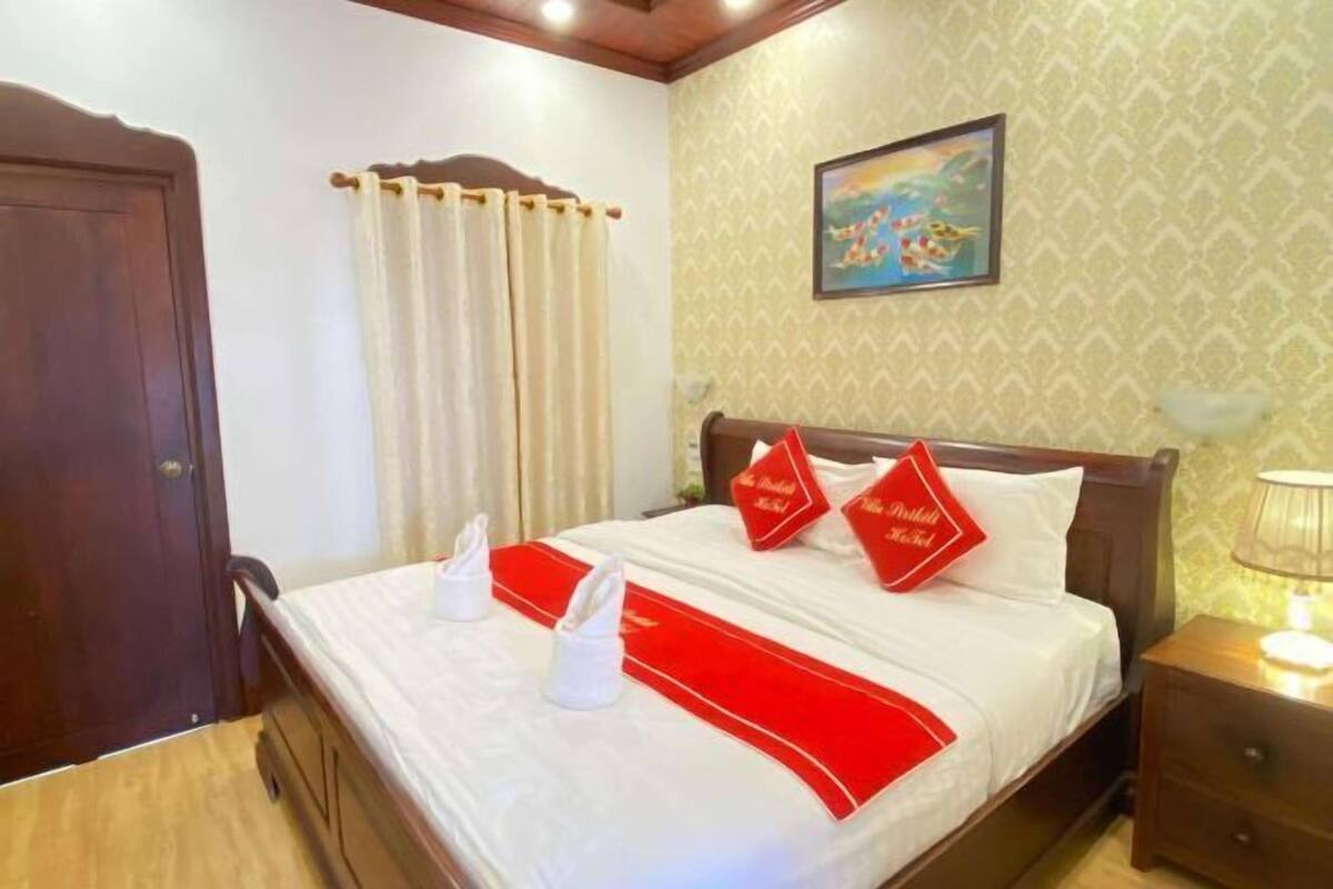 Une chambre d’hôtel avec un lit, des rideaux, un tableau et une table de chevet.