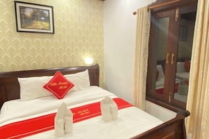 Une chambre d’hôtel comprenant un lit, une table de chevet, un miroir et une armoire.