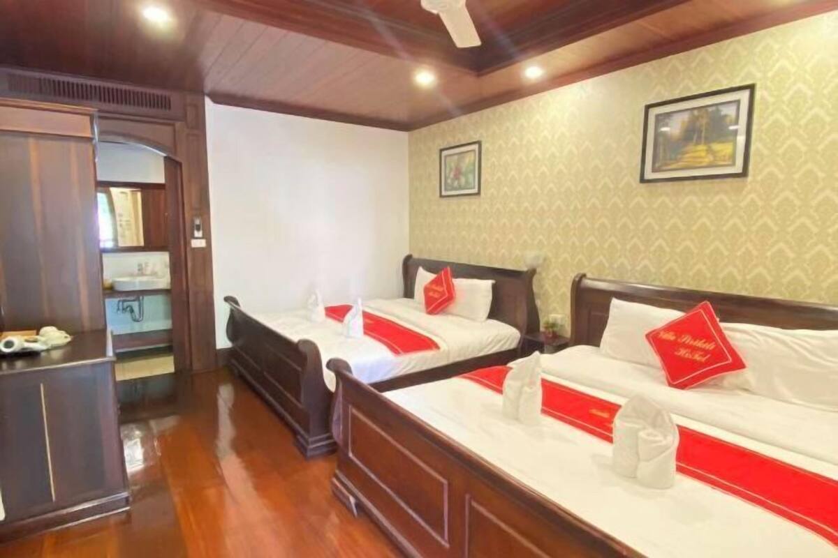 Une chambre d’hôtel avec deux lits, des têtes de lit en bois, un petit bureau et un miroir.