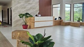 A modern reception area with a marble reception desk, large windows, and indoor plants. - Lotus Resort Panglao (Panglao)