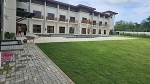A multi-story building with a courtyard, a paved walkway, and a grassy lawn. - Lotus Resort Panglao (Panglao)