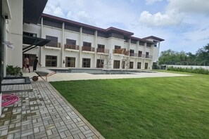 Un immeuble à plusieurs étages doté d’une cour intérieure, d’une allée pavée et d’une pelouse.