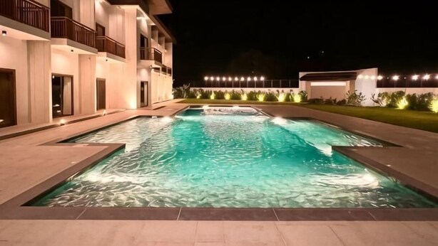 A swimming pool with a building in the background. - Lotus Resort Panglao (Panglao)
