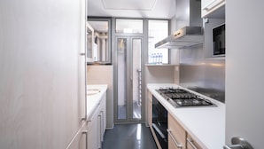 A narrow commercial kitchen with stainless steel appliances, a gas stove, and a microwave. - Tyms Elegant 2BR 1BA Apt Walk to Malls (Shanghai)