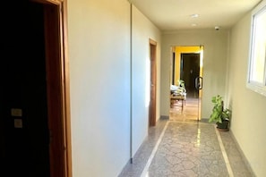 A hallway with a tiled floor, a door on the left, and a window on the right. - Al Dora All Inclusive Hotel (Hurghada)