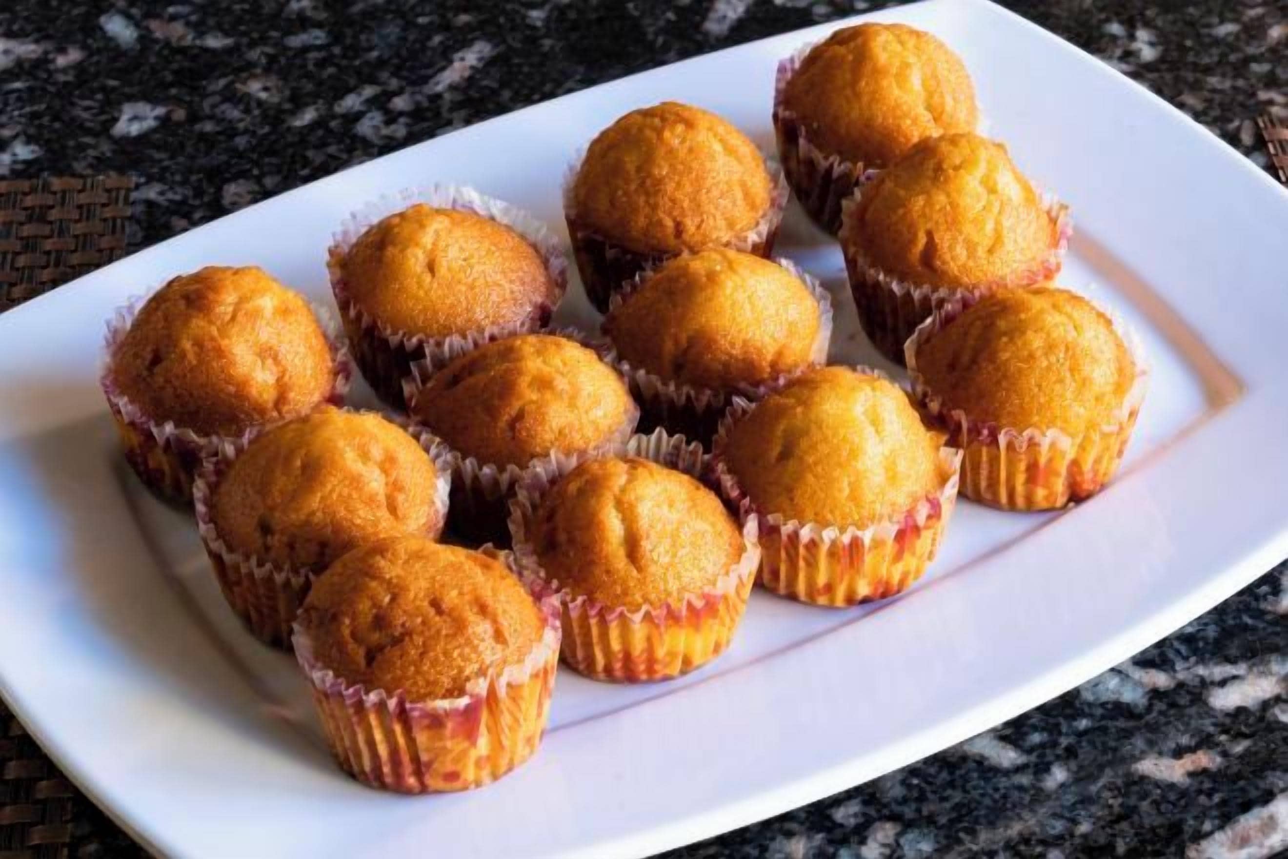 A white plate with round, golden-brown baked goods in paper cups.