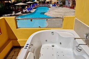 Un área de piscina con jacuzzi y sillones de descanso.