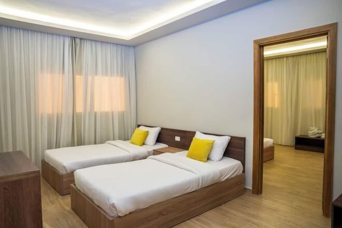 Ein Hotelzimmer mit zwei Betten, Holzkopfteilen, einem Spiegel, einem Holztisch und einem Kleiderschrank.