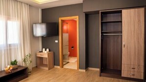 A modern hotel room with a wooden floor, a large wardrobe, a television, and a small desk with a plant. - Al Dora All Inclusive Hotel (Hurghada)