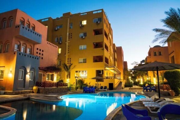 Un hôtel doté d’une piscine, d’un espace extérieur aménagé et d’une façade bien éclairée.