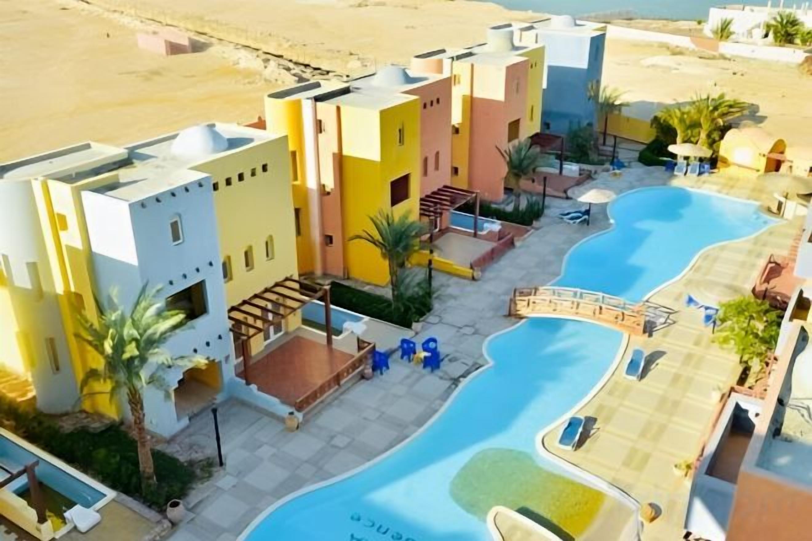 Een hotel met meerdere gebouwen, een zwembad en uitzicht op het strand.