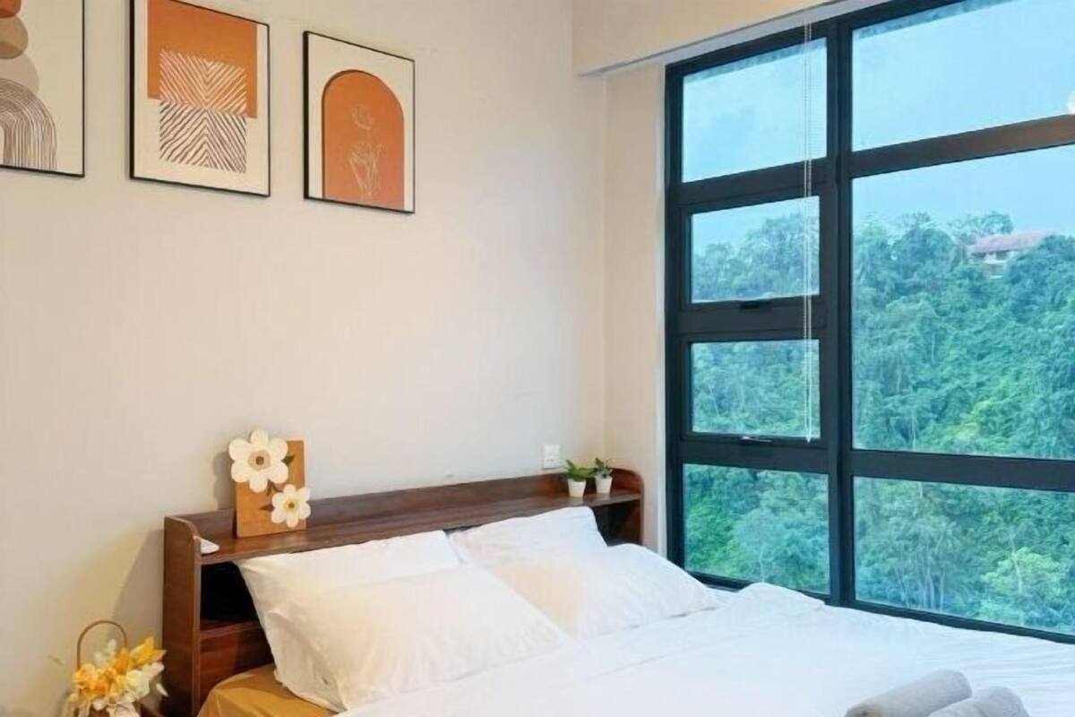Quarto com uma janela ampla, cabeceira de madeira, cama com roupa de cama branca e quadros na parede.