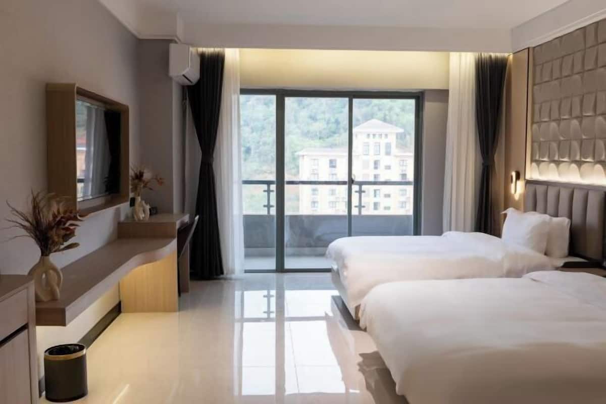 A hotel room with two beds, a large window with a view of buildings, a flat-screen TV, and a modern design.