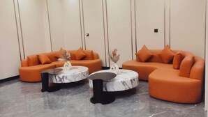 A modern living room with two orange sofas and two round coffee tables with marble tops. - Starry Sky Resort Hotel (Boten)