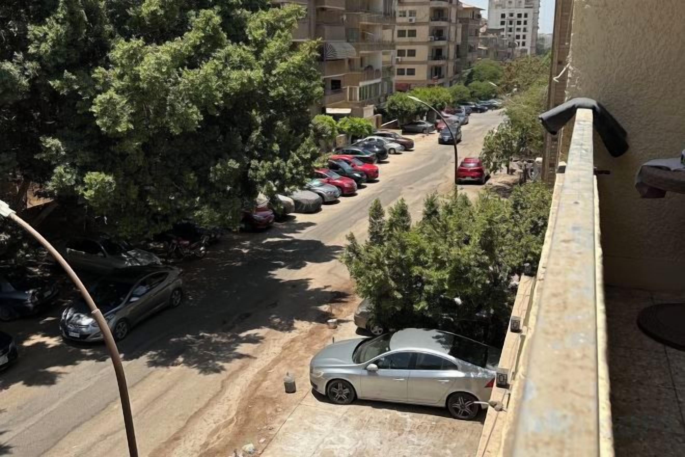 A street view with parked cars and buildings in the background.