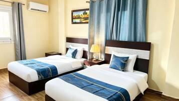 A hotel room with two beds, a nightstand, a lamp, and a painting on the wall.