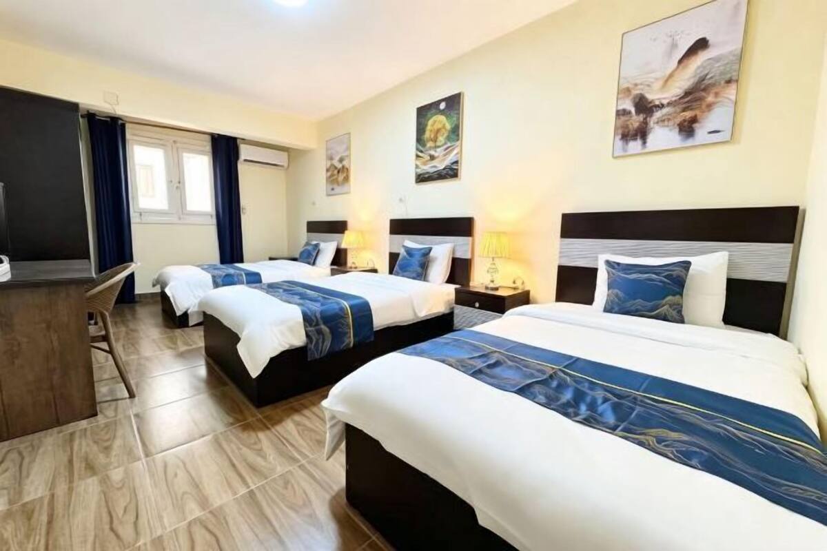 A hotel room with three beds, a desk, and a chair.