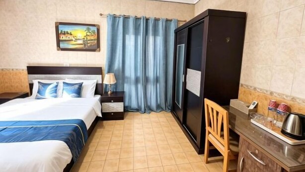 Habitació d'hotel amb llit, una vetusta, escriptori, cadira i armari.