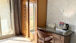 Habitació amb porta corredissa, taula de vidre amb tetera, cadira i un petit armari.