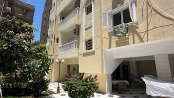 A multi-story building with balconies, outdoor seating, and a covered area with a table and chairs.