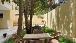 Un pati amb taula i cadires, envoltat per un mur baix i arbres.