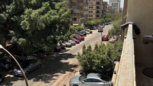 Vista d'un carrer amb cotxes estacionats i arbres.
