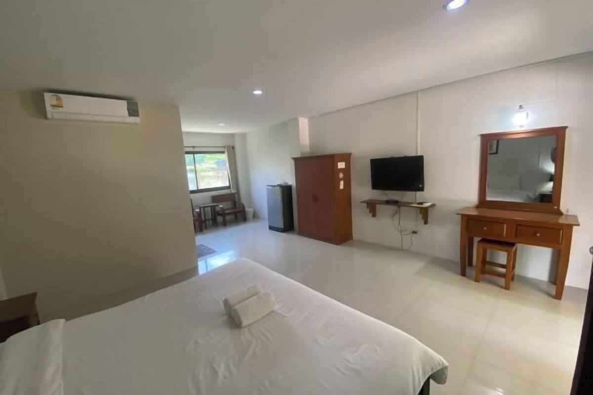 A hotel room with a bed, a TV, a wooden dresser, and a desk.