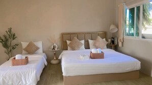 A hotel room with two beds, each with white linens and decorative pillows. There is a bedside table with a lamp and a small plant. - Imboutique hotel Maesot (Mae Sot)