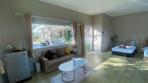 A living room with a sofa, a coffee table, a bed, and a refrigerator. - Imboutique hotel Maesot (Mae Sot)