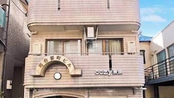 A building with a sign that reads 'cozy hotel' and a clock above the entrance.