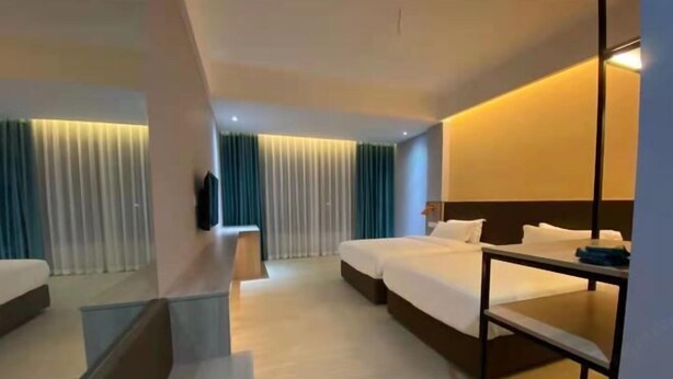Ein Hotelzimmer mit zwei Betten, einem Schreibtisch und einem Fernseher.