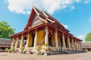 A traditional building with a red roof, multiple columns, and a staircase leading to the entrance. - Fucheng International Hotel (Vientiane)