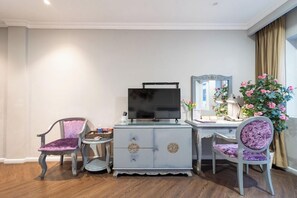 Una habitación con televisión, dos sillones, escritorio y espejo.