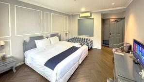 Une chambre d’hôtel avec un grand lit, un coin salon, une télévision et une porte.
