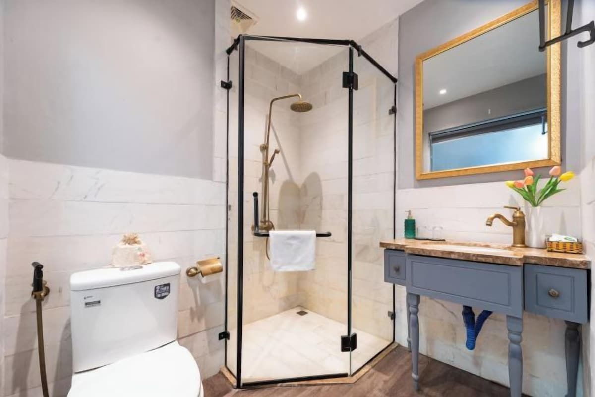 Un baño moderno con ducha envuelta en vidrio, inodoro y tocador con espejo.