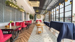 Un restaurante con sillas rojas, suelo estampado y vistas amplias a través de grandes ventanales.