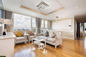 Un salon spacieux, doté d’un ensemble de canapés, d’une table basse et offrant une vue sur la ville.