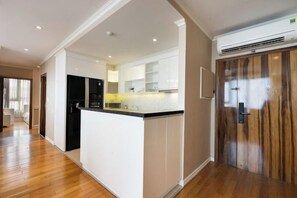 Une cuisine moderne dotée d’un îlot central, d’appareils électroménagers intégrés et d’une porte en bois.
